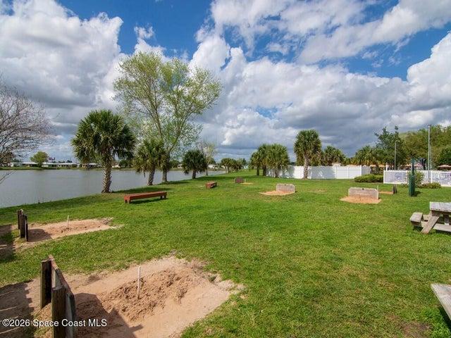 Expansive green space featuring multiple palm trees, horseshoe pits, and wooden benches