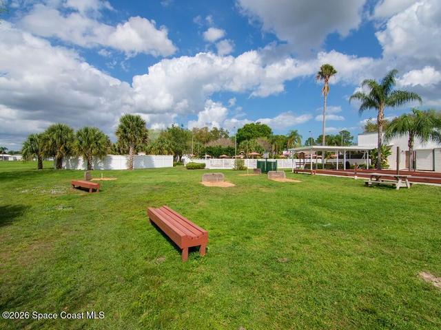 Expansive green space featuring multiple palm trees, horseshoe pits, and wooden benches