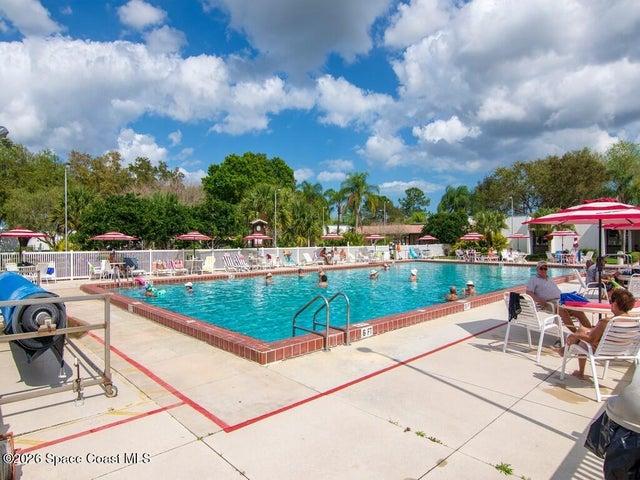 Rectangular swimming pool featuring a brick coping, concrete deck, and perimeter fencing
