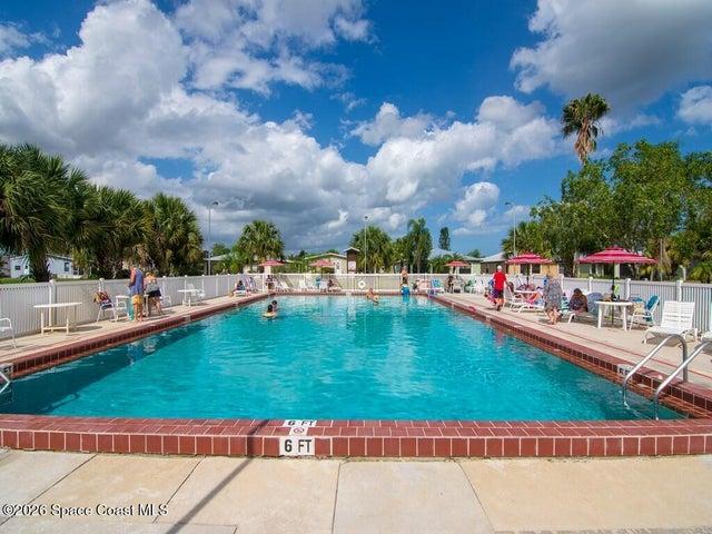 Rectangular swimming pool featuring a brick coping, concrete deck, and perimeter fencing