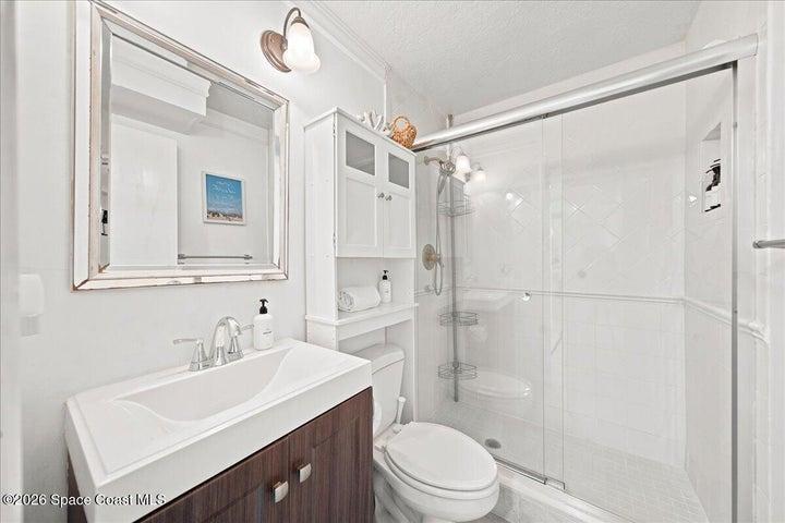 Updated guest bathroom featuring a modern vanity, spacious walk-in shower, contemporary fixtures, and built-in shelving for a clean, stylish, and functional space.