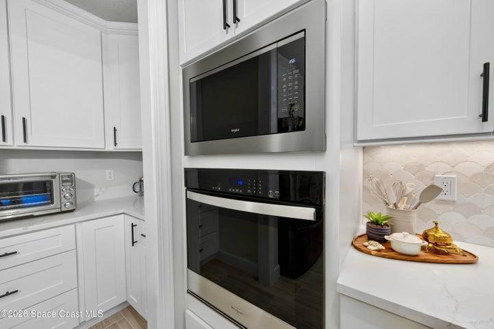 Left - BUTLERS PANTRY and Appliance Center.  A functional and aesthetic fluid extenstion of the kitchen: Quartz countertop, Ideal prep-station and/or coffee bar, Motion-sensor lighting, Custom cabinetry with pot drawers, soft close, two Lazy Susans, 42" Upper cabs++.