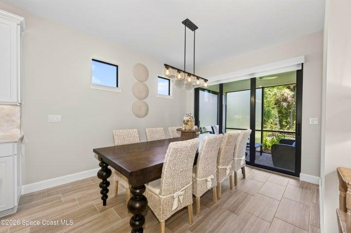 DINING AREA -Triple sliders added in lieu of window to enhance indoor/outdoor living and tropical preserve views. Two transom windows. Designer Chandelier.