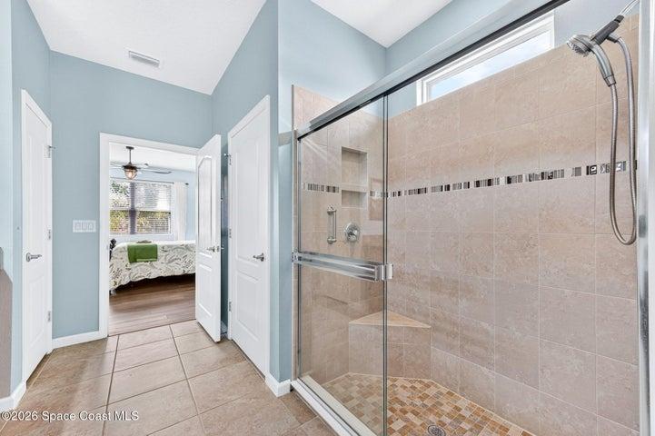 Spacious walk-in tiled shower with natural light and built in seat