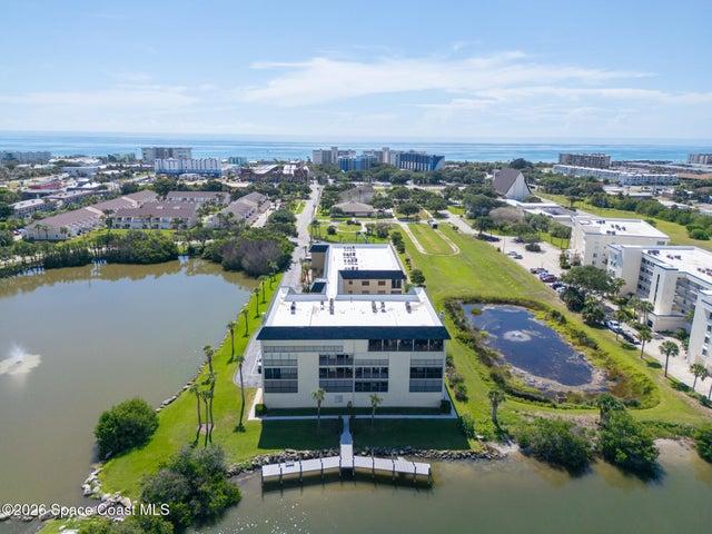 Aerial view of Riverwest condominium property with pond, fishing dock, and ocean view in the distance