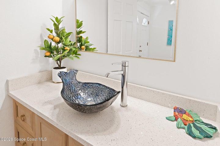 Powder bathroom vessel sink with Quartz countertop, wood-tone cabinetry and chrome faucet — Riverwest condo, Cocoa Beach
