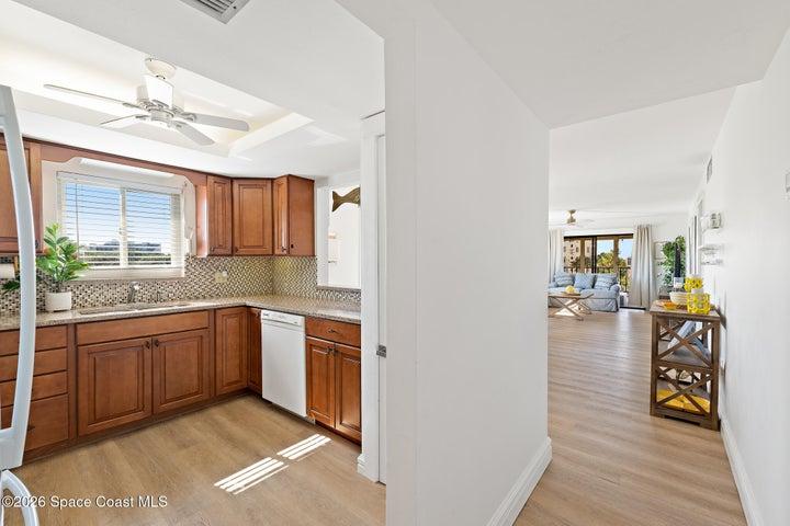 Kitchen with wood cabinetry and granite counters opening to living area — 2-bedroom condo, Cocoa Beach