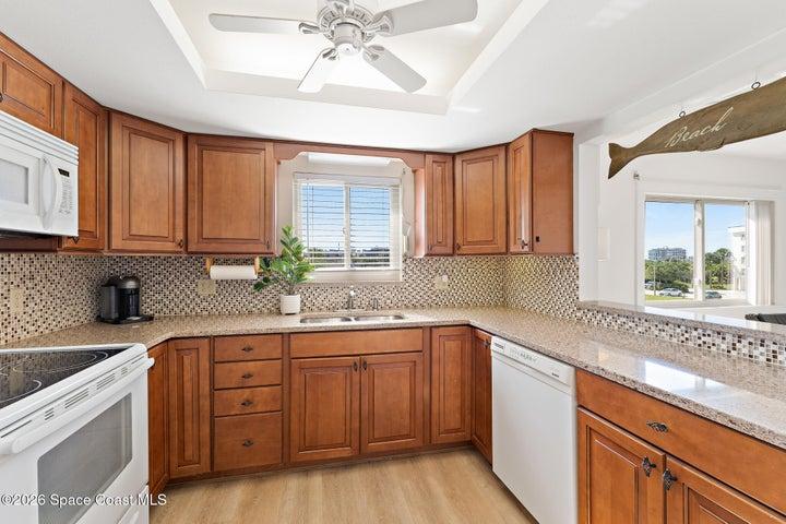 Updated kitchen with granite countertops, tile backsplash, and wood cabinetry — Riverwest condo