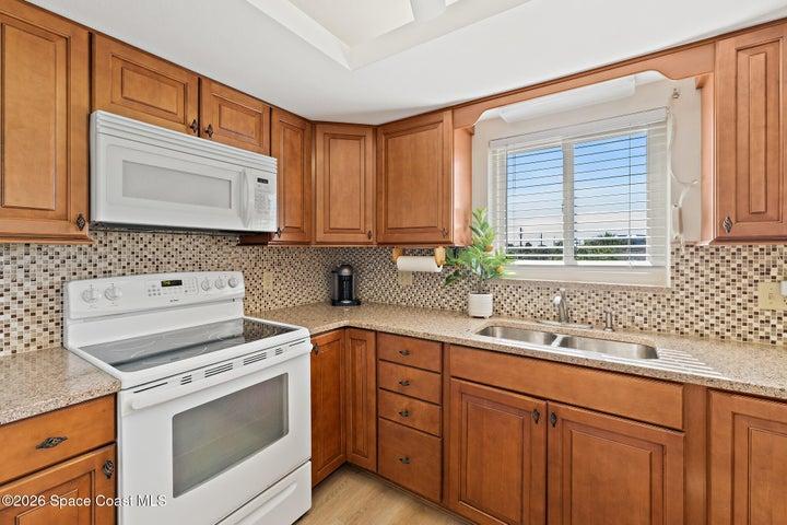 Kitchen with tray ceiling, granite counters, and tile backsplash — Riverwest condo, Cocoa Beach