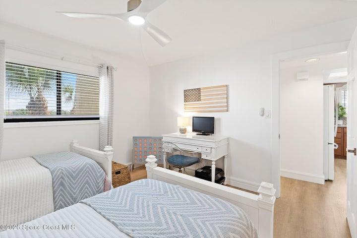 Guest bedroom with desk, ceiling fan, and natural light — Riverwest condo, Cocoa Beach
