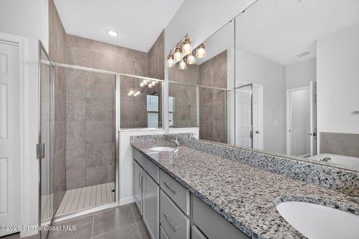 Primary ensuite with granite countertop, double sinks, and walk-in shower