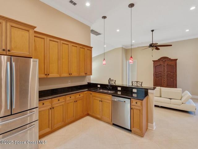Kitchen with appliances with stainless steel finishes, pendant lighting, open floor plan, a peninsula, and brown cabinets