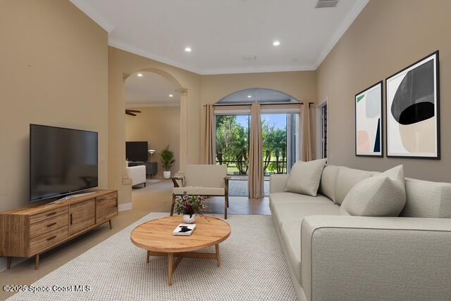Family room featuring arched walkways, french doors, light tile patterned floors, and crown molding