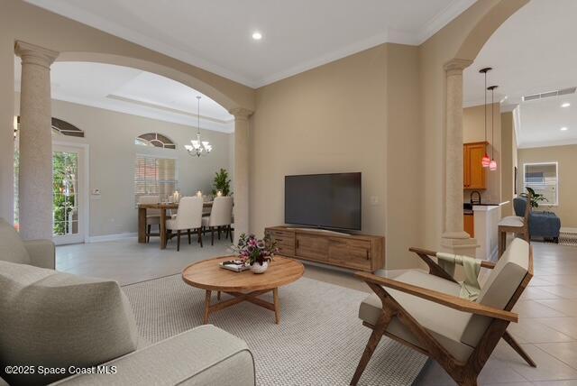 Living room featuring arched walkways, french doors, light tile patterned floors, and crown molding