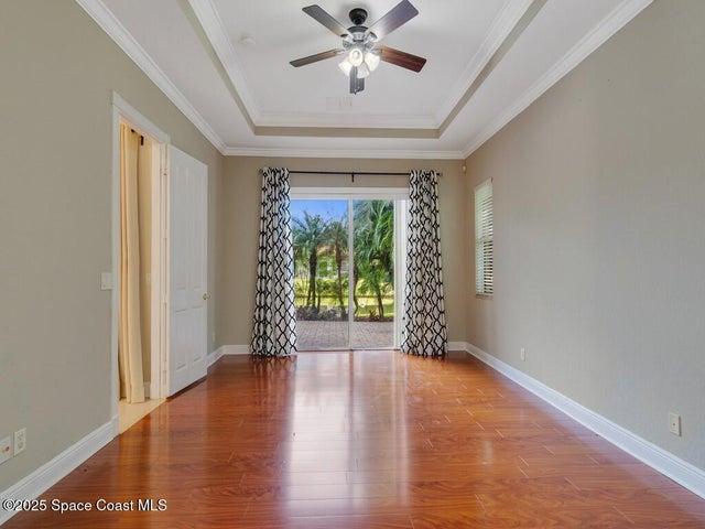 Unfurnished room with wood finished floors, ornamental molding, a raised ceiling, and ceiling fan