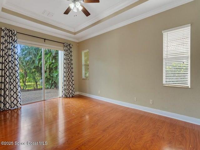 Unfurnished room with wood finished floors, crown molding, a tray ceiling, and ceiling fan