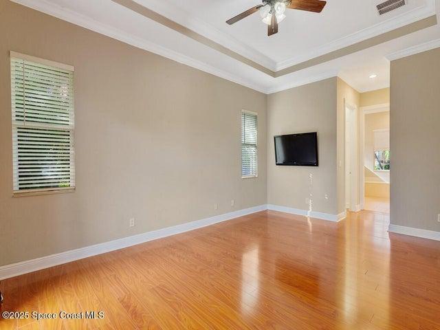 Unfurnished room with wood finished floors, crown molding, a tray ceiling, and ceiling fan