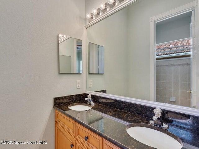 Full bathroom with double vanity and a textured wall