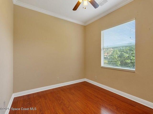 Unfurnished room with crown molding, wood finished floors, and a ceiling fan