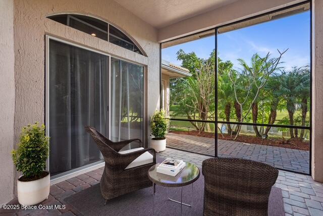 Sunroom / solarium featuring brick floors and a textured wall