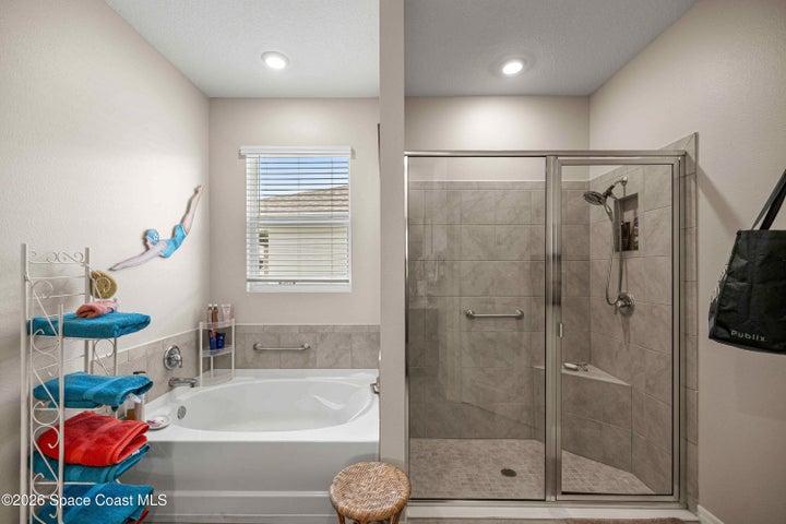 Bathroom featuring a built-in soaking tub with tiled surround, a walk-in shower with glass enclosure, tiled walls, and a built-in shower bench