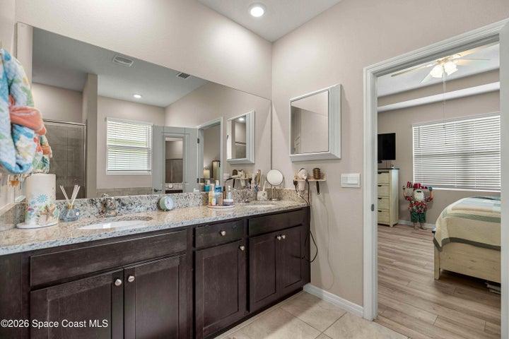 Bathroom featuring a double vanity with dark wood cabinetry, light speckled countertop, and dual integrated sinks