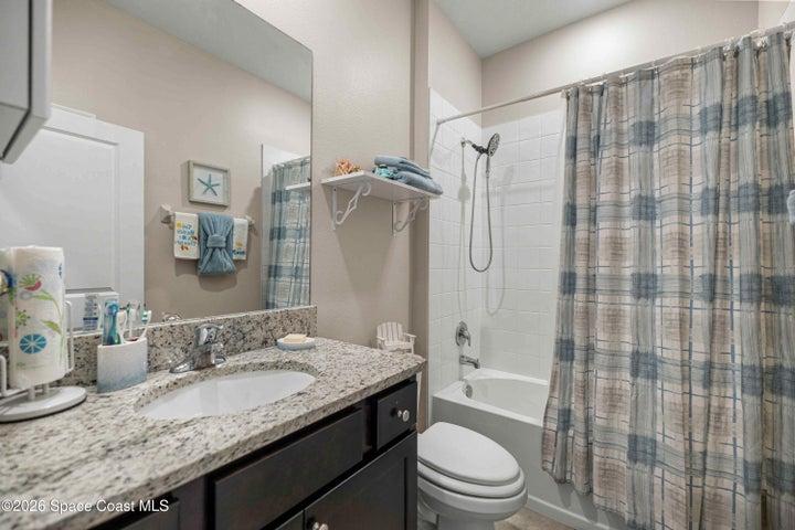Bathroom featuring a vanity with a light-toned stone countertop, undermount sink, and dark cabinetry