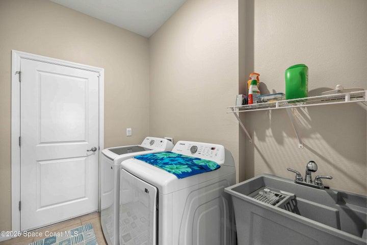 Utility room featuring a built-in wash basin, wire shelving, and neutral tone walls