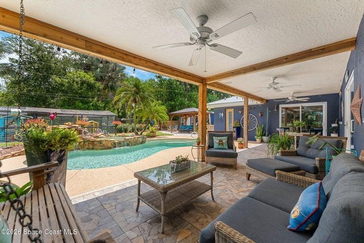 Covered poolside patio finished with warm cedar accents, creating an inviting outdoor living and dining space.