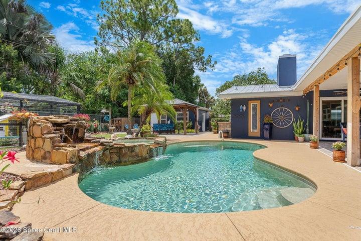 Freeform pool featuring a durable PebbleTec surface and a relaxing rock waterfall.