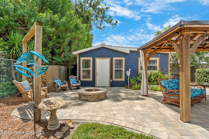 Welcoming front entrance to the pool house featuring a spacious paver patio, fire pit, covered gazebo, and plenty of outdoor seating.