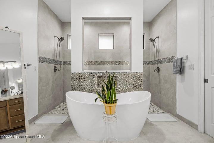 Designed for relaxation, the primary bath features a freestanding soaking tub framed by dual walk-in showers, creating a spa-inspired retreat with timeless finishes and thoughtful design.