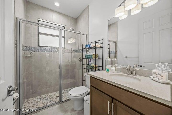 Featuring a spacious walk-in tiled shower, quartz vanity, and modern finishes, this full bath offers both comfort and convenience for guests or multigenerational living.