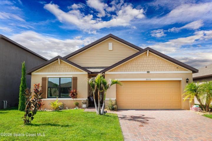 Welcoming front exterior featuring attractive landscaping, a paver driveway, and a two-car garage.