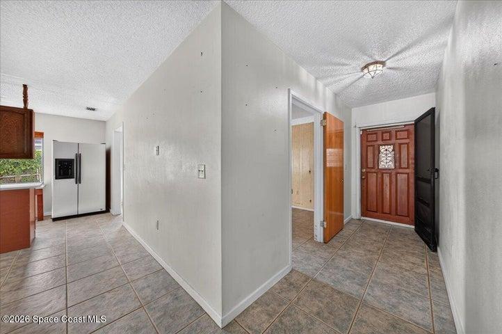 Entryway with room on the left, laundry room out of view, and a bit of the kitchen is in view