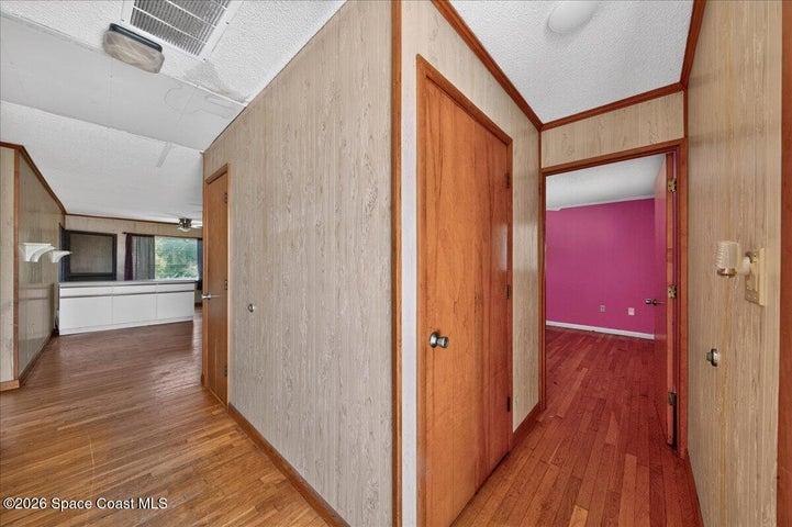 Entryway with view of front bedroom on the right, the wooden door leads upstairs to a large attic, and to the left leads you to the living area and kitchen.