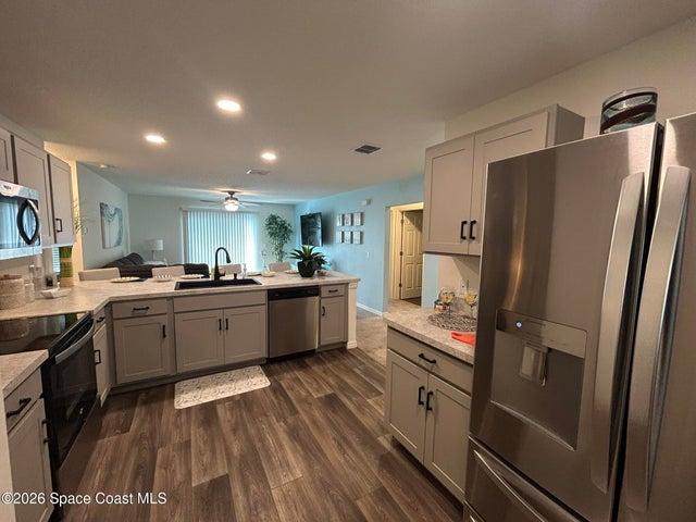 Kitchen featuring light grey cabinetry with black hardware, stainless steel appliances, and vinyl plank flooring.