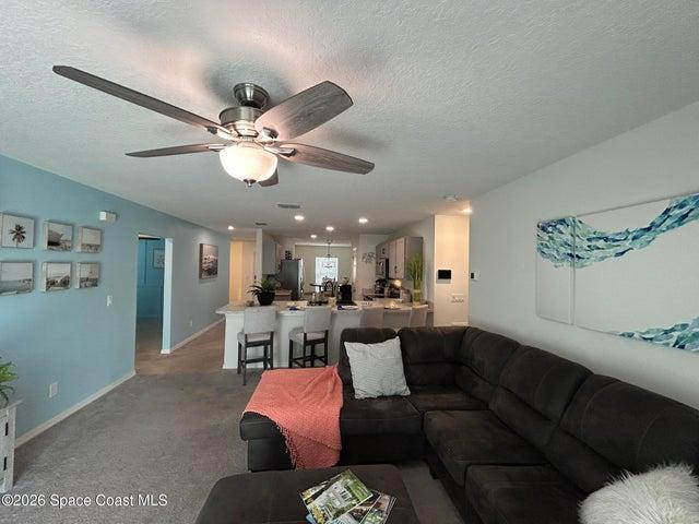 Spacious living area featuring light-toned carpeting and neutral wall colors