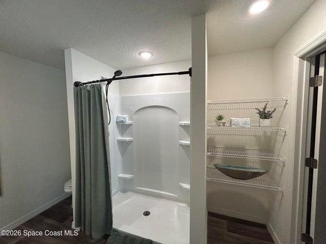 Primary bath featuring a walk in shower and vinyl plank flooring.