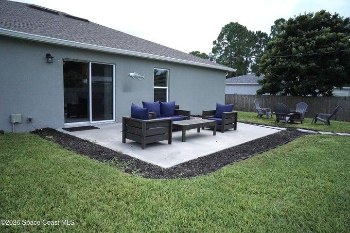 Expansive backyard featuring a lush lawn, privacy fencing, and a concrete patio