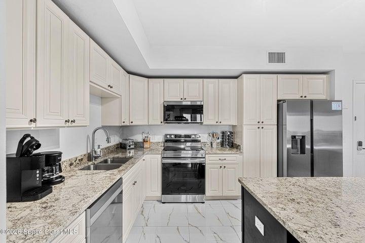 The modern kitchen combines solid wood cabinetry, granite surfaces and under-cabinet lighting in a clean, functional design.