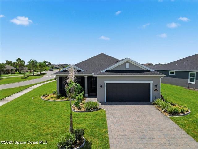 Charming front exterior of 8138 Dobre Way showcasing lush landscaping and curb appeal in the Addison Village community, Melbourne, FL