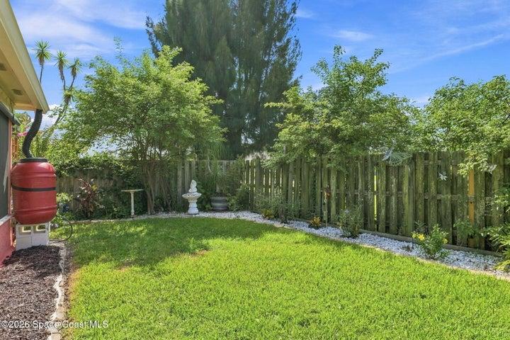 Well-maintained, fully fenced backyard featuring lush landscaping and an abundance of mature plants, creating a private and inviting outdoor retreat.