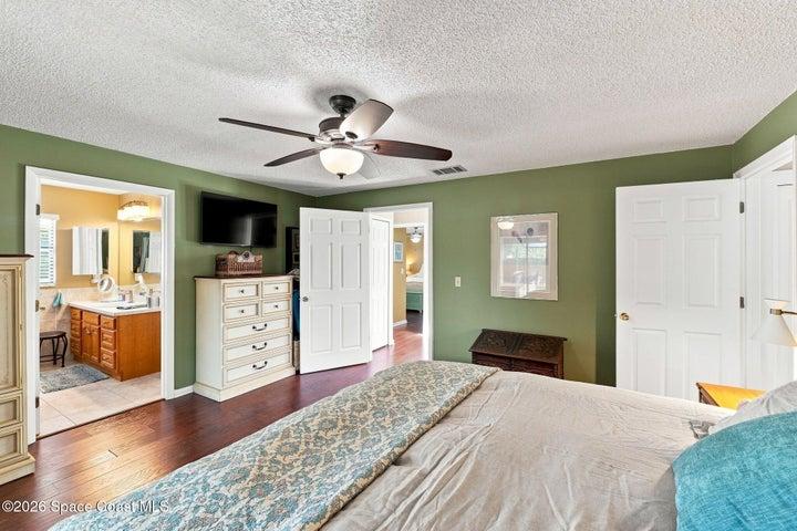Primary bedroom featuring a private en-suite bathroom, large walk-in closet, and direct access to the screened-in lanai.