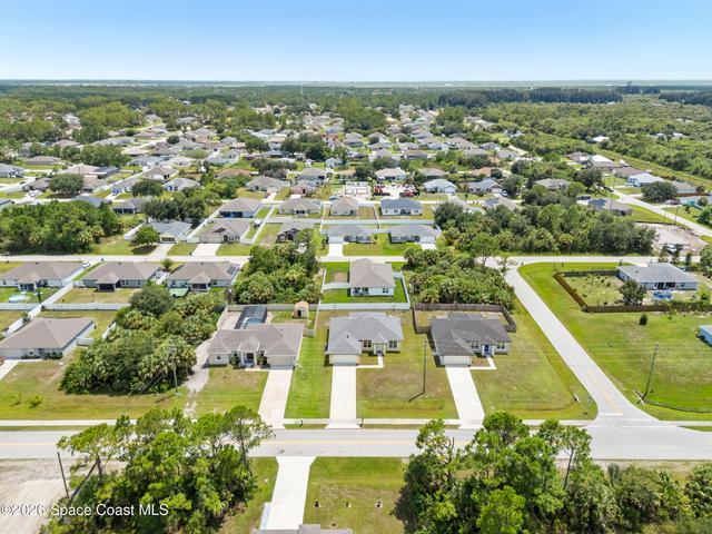 Bird’s-eye view highlighting the home, driveway, and surrounding landscape