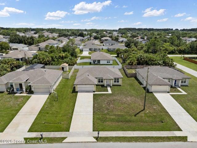 Bird’s-eye view highlighting the home, driveway, and surrounding landscape
