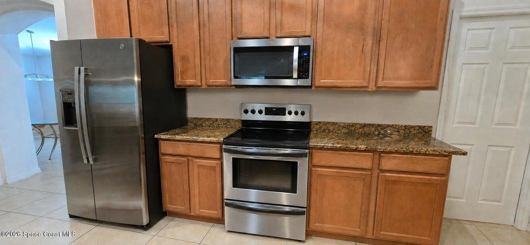 Kitchen with granite counters. Digitally decluttered.