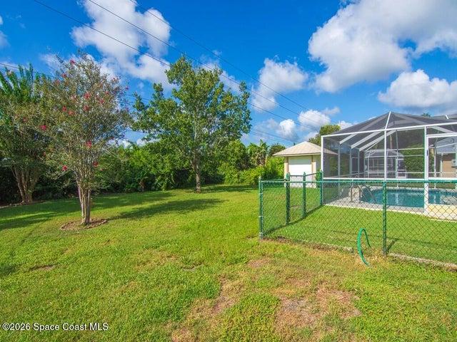 Fenced dog run with screened pool cage in the background