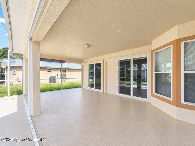 Covered patio shot from the pool bathroom. Living room and primary sliders