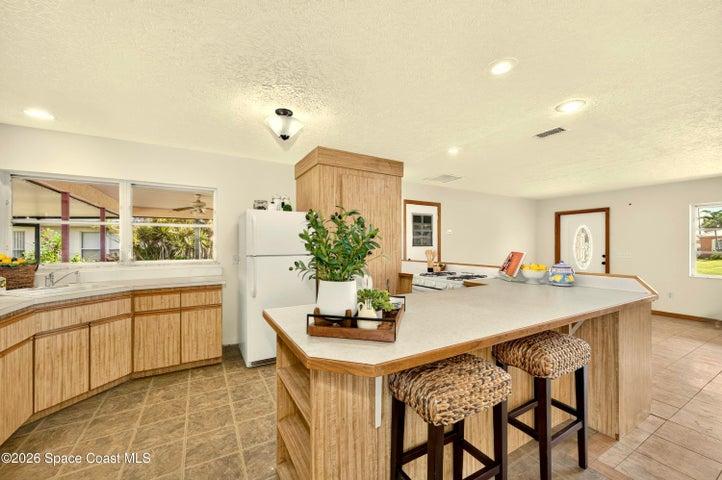 KITCHEN opens to living and dining areas. Looks out to covered lanai and spacious backyard. IMAGINE THE POTENTIAL!